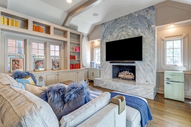 living room featuring lofted ceiling, a premium fireplace, hardwood / wood-style floors, and built in features