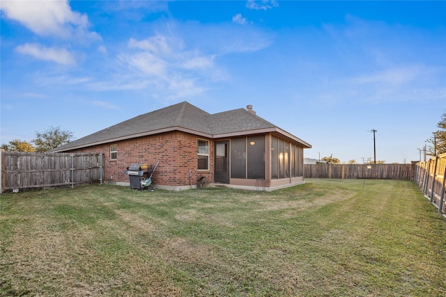 back of property with a sunroom and a yard