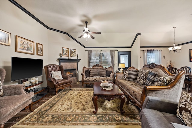 living room featuring a tiled fireplace, crown molding, hardwood / wood-style flooring, and ceiling fan with notable chandelier