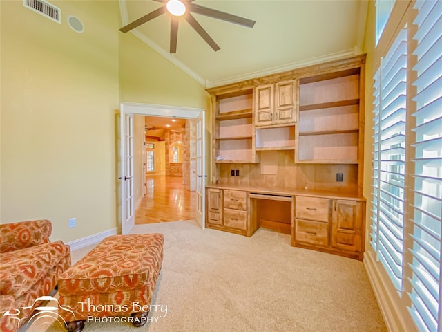 home office featuring crown molding, ceiling fan, high vaulted ceiling, built in desk, and light carpet