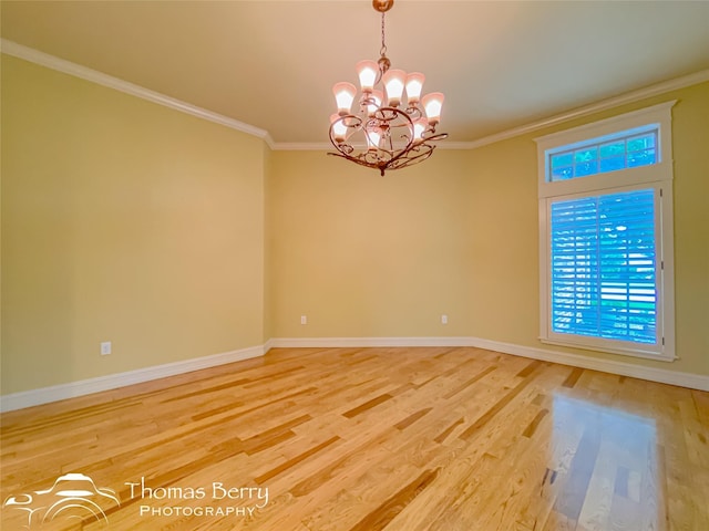 empty room featuring ornamental molding, hardwood / wood-style floors, and a notable chandelier