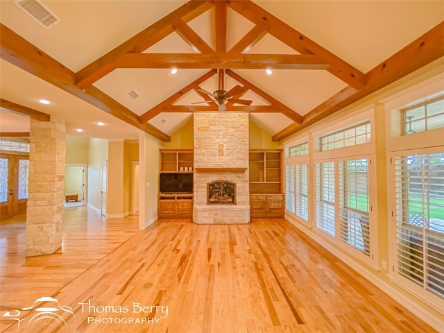 unfurnished living room with hardwood / wood-style floors, a fireplace, beamed ceiling, and ornate columns