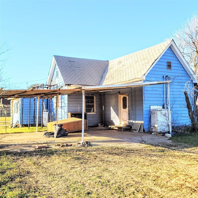 back of property with a lawn and a hot tub