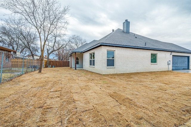 back of property with a garage and a yard