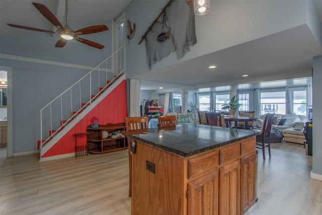 kitchen featuring ceiling fan, a high ceiling, a kitchen island, and light wood-type flooring