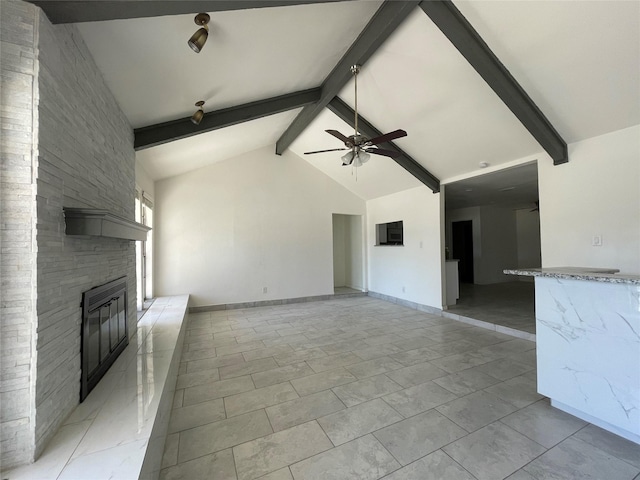 unfurnished living room with ceiling fan, a stone fireplace, high vaulted ceiling, and beam ceiling