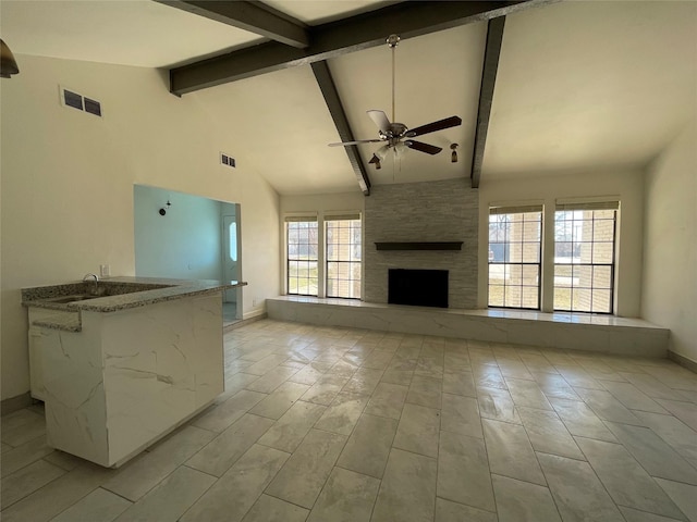 unfurnished living room with beam ceiling, high vaulted ceiling, a fireplace, and ceiling fan