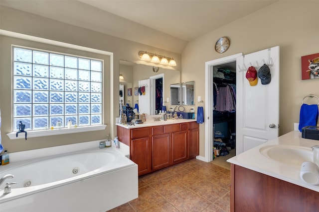 bathroom with vanity, tile patterned flooring, vaulted ceiling, and a tub