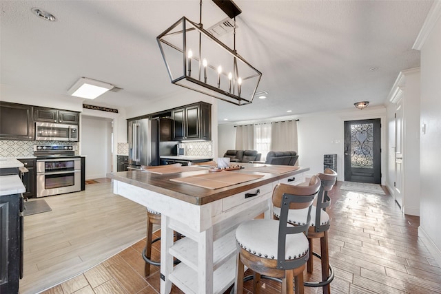 kitchen featuring hanging light fixtures, appliances with stainless steel finishes, dark brown cabinetry, and light wood-type flooring