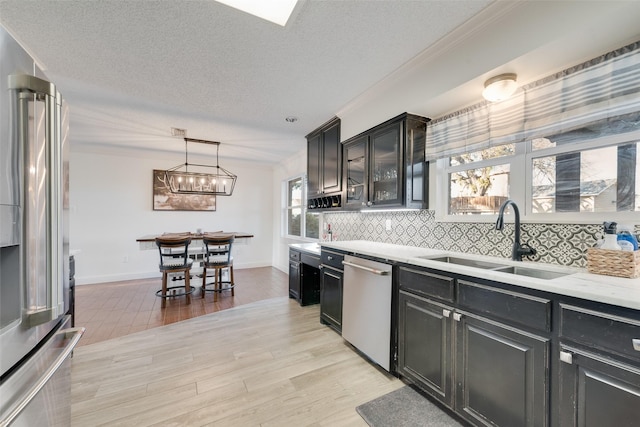 kitchen featuring pendant lighting, tasteful backsplash, sink, stainless steel dishwasher, and high end fridge