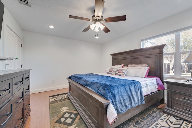 bedroom with ceiling fan, dark hardwood / wood-style floors, multiple windows, and a textured ceiling