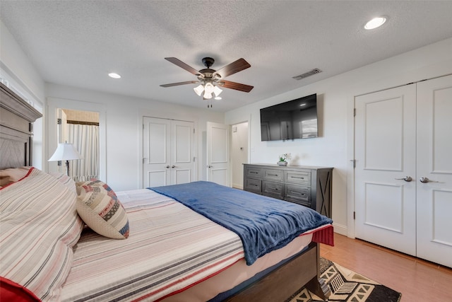 bedroom featuring ceiling fan, light hardwood / wood-style floors, and a textured ceiling