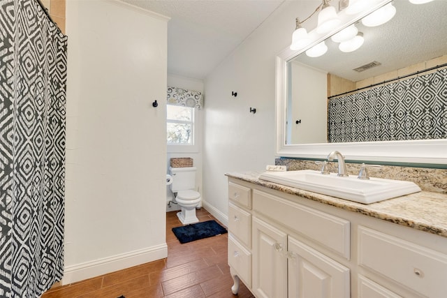 bathroom with vanity, wood-type flooring, toilet, and a textured ceiling