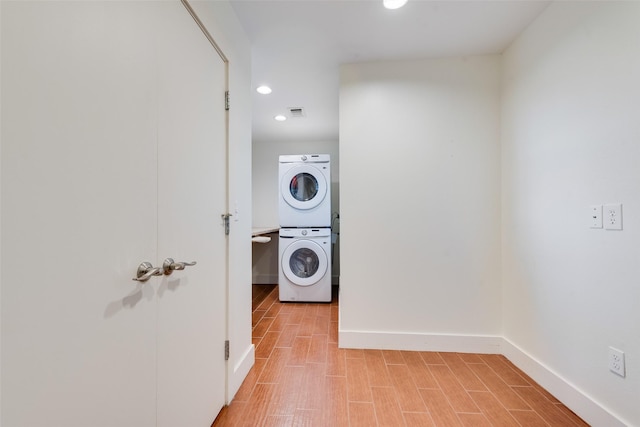 laundry area featuring stacked washer and dryer and light hardwood / wood-style floors