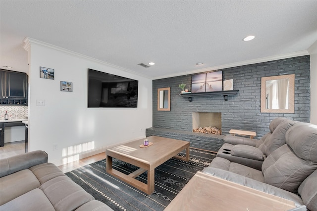 living room featuring hardwood / wood-style flooring, ornamental molding, a fireplace, and a textured ceiling