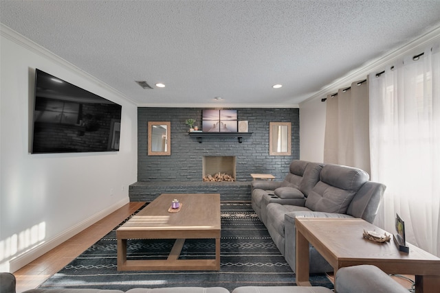 living room featuring ornamental molding, wood-type flooring, a brick fireplace, and a textured ceiling