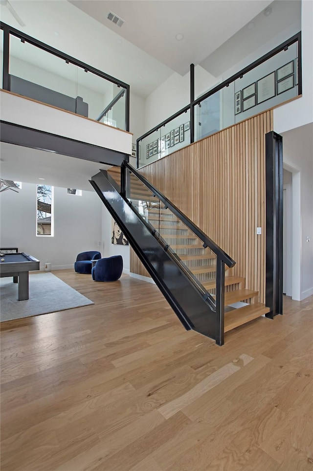 stairway with hardwood / wood-style floors, a towering ceiling, and pool table