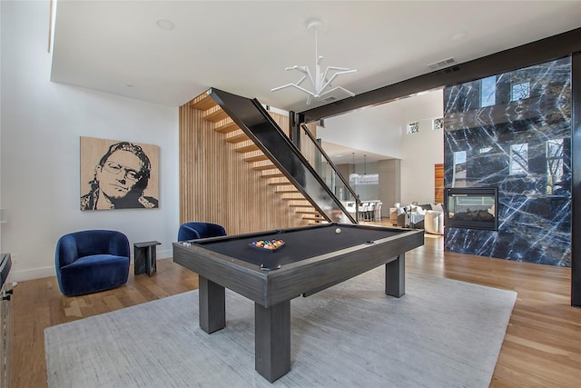 recreation room featuring hardwood / wood-style flooring, a premium fireplace, pool table, and a chandelier