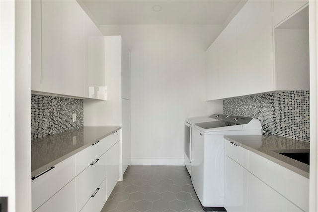 laundry area featuring dark tile patterned flooring, sink, cabinets, and washing machine and clothes dryer