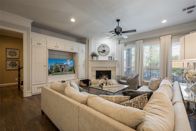 living room with a fireplace, dark wood-type flooring, ornamental molding, and ceiling fan