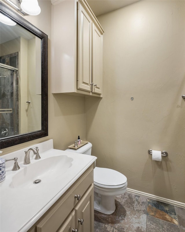 bathroom featuring vanity, a shower with door, and toilet