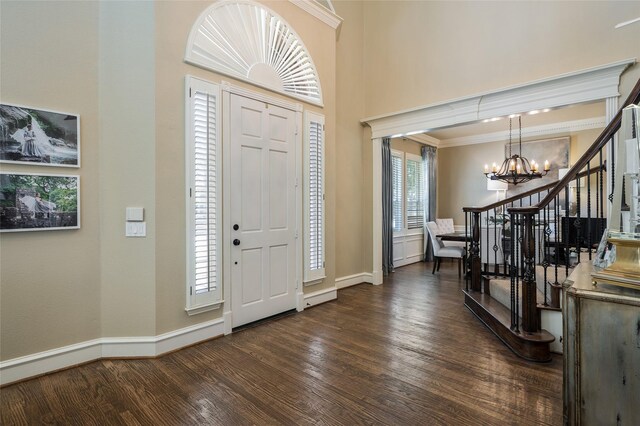 foyer featuring an inviting chandelier, a towering ceiling, dark hardwood / wood-style floors, and crown molding