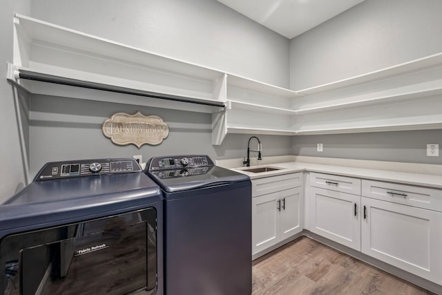 clothes washing area featuring sink, light hardwood / wood-style floors, cabinets, and washing machine and dryer