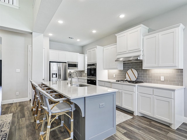 kitchen with a breakfast bar, white cabinetry, sink, a kitchen island with sink, and stainless steel appliances