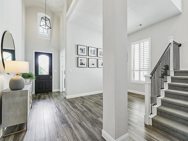 foyer with a high ceiling, stairway, baseboards, and dark wood-style flooring