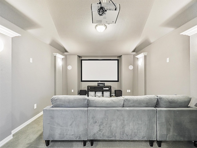 home theater room with carpet flooring, a textured ceiling, and ornate columns