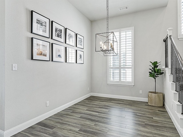 unfurnished dining area with an inviting chandelier and dark hardwood / wood-style floors