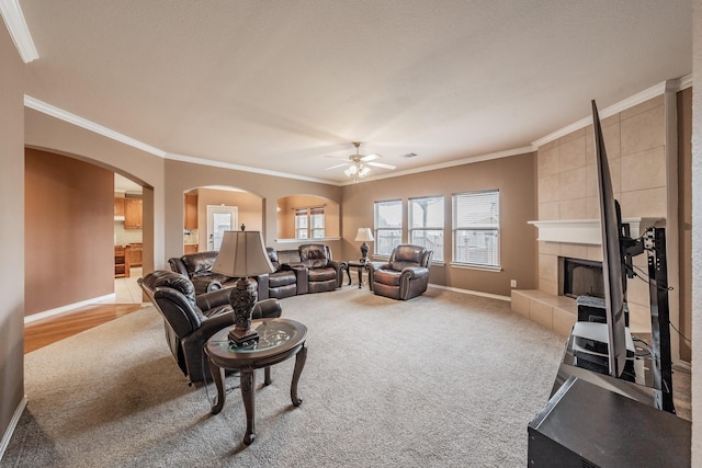 carpeted living room featuring crown molding, ceiling fan, and a fireplace