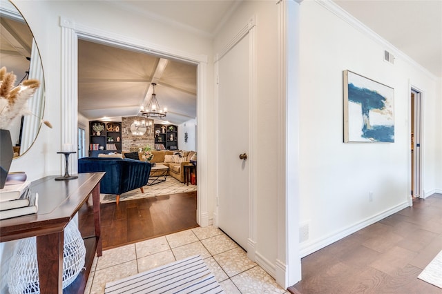 corridor with crown molding, lofted ceiling, light tile patterned flooring, and a notable chandelier