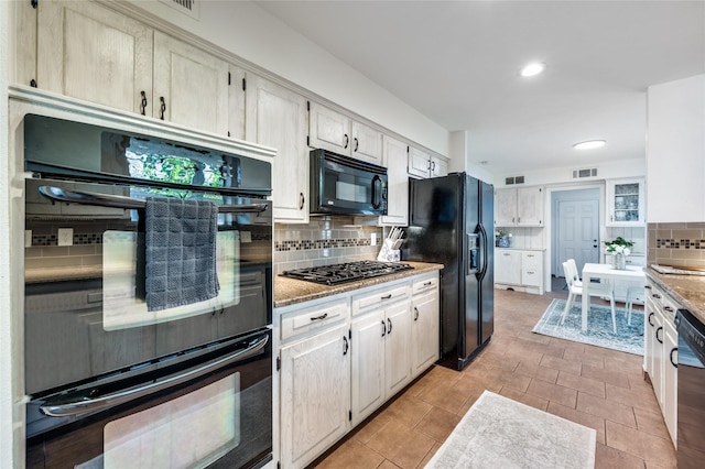 kitchen featuring backsplash, light tile patterned flooring, black appliances, and light stone countertops