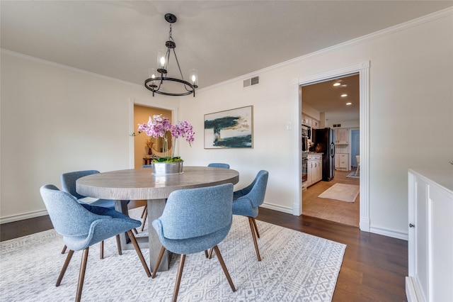 dining space with an inviting chandelier, dark wood-type flooring, and ornamental molding