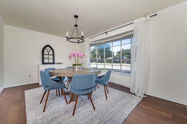 dining room featuring dark wood-type flooring, ornamental molding, a chandelier, and a textured ceiling