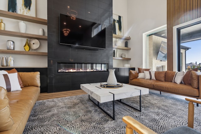 living room featuring built in shelves, wood-type flooring, and a tile fireplace