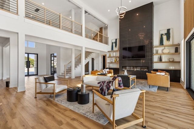 living room featuring a towering ceiling, a fireplace, and light wood-type flooring