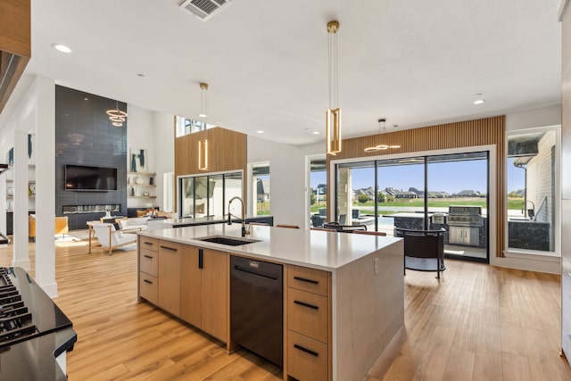 kitchen featuring a center island with sink, sink, pendant lighting, and light brown cabinets