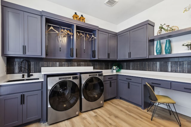 clothes washing area featuring cabinets, sink, independent washer and dryer, and light hardwood / wood-style flooring