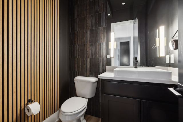 bathroom with vanity, tile walls, and toilet