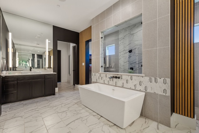 bathroom with vanity, shower with separate bathtub, and tile walls