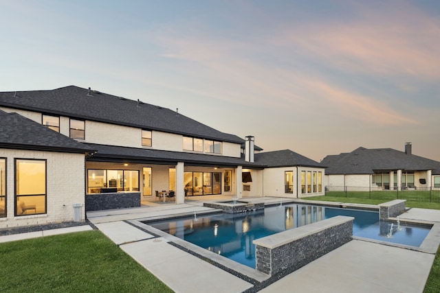 pool at dusk with an in ground hot tub, a lawn, and a patio area