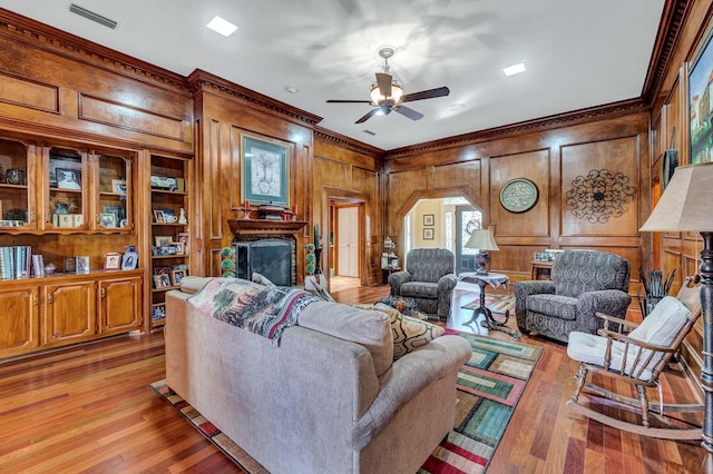 living area with visible vents, a fireplace, light wood-style flooring, and crown molding