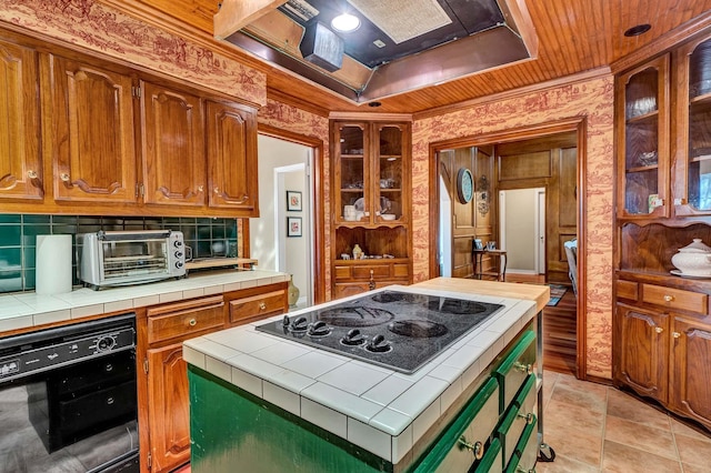 kitchen featuring wall chimney exhaust hood, electric cooktop, tile counters, and a toaster