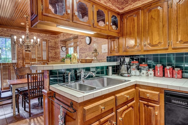 kitchen with brown cabinetry, black dishwasher, a sink, and tile countertops