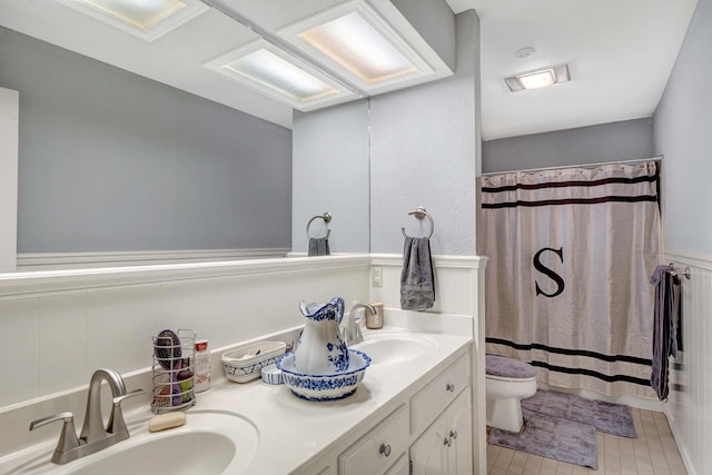 bathroom with toilet, a shower with curtain, double vanity, and a sink