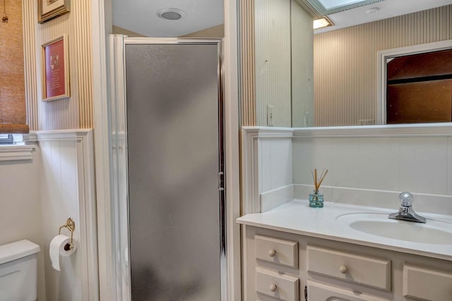 bathroom with toilet, a stall shower, wallpapered walls, and vanity