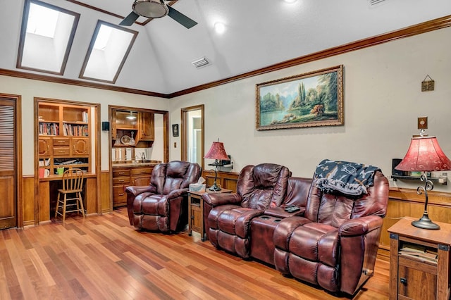 living room featuring lofted ceiling, crown molding, ceiling fan, built in desk, and light wood-type flooring