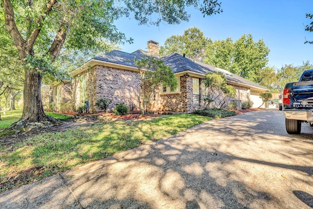 ranch-style house with driveway, a chimney, a front lawn, and brick siding